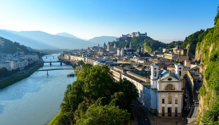 Luftaufnahme von Salzburg, Österreich, mit dem Fluss Salzach, historischen österreichischen Gebäuden und einer Festung auf dem Berggipfel.
